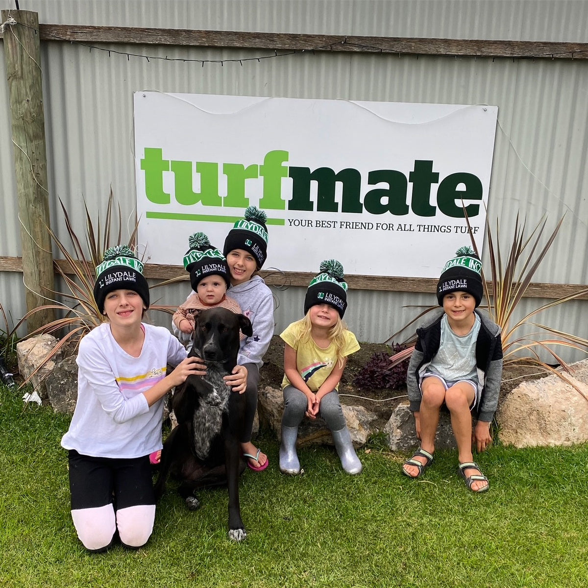 The Turfmate family and their dog together beneath a Turfmate sign.