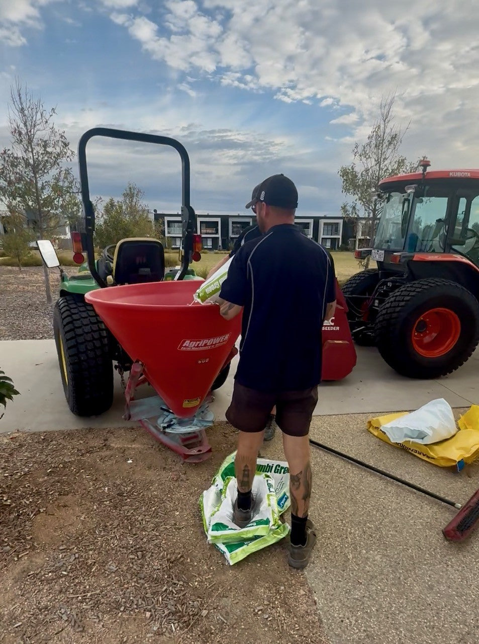 Turfmate crew with a red fertiliser spreader and tractor